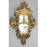 A 19thC giltwood wall mirror, of cartouche form decorated with scrolls, masks, flowers, etc, 89cm