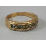 A ladies half eternity ring, set with green and white stones, on a yellow metal ground, marks