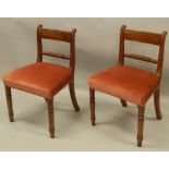 A pair of early 19thC mahogany bar back dining chairs, each with a padded seat, on turned legs.