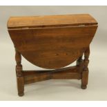 A reproduction oak drop leaf table, on turned supports, oval top, 73cm wide.