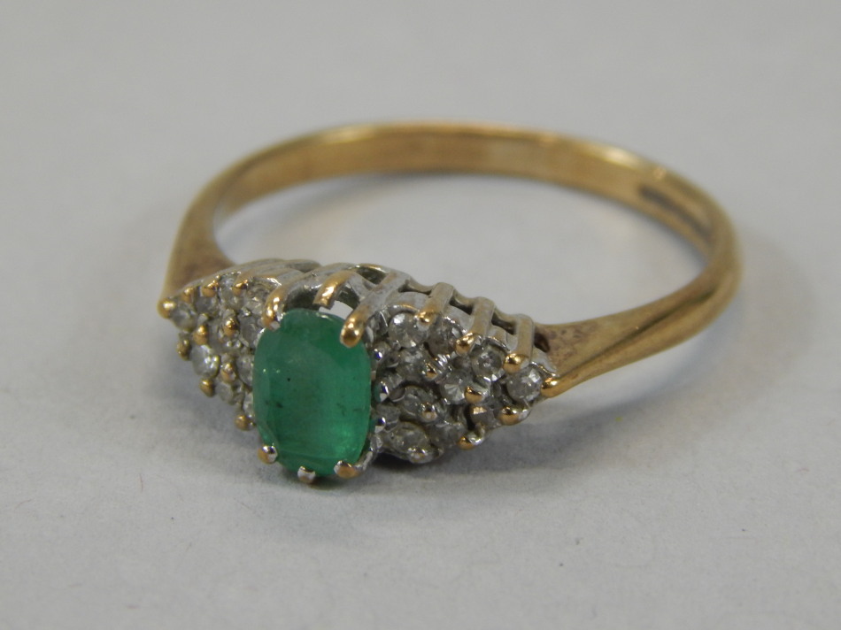 A 9ct gold dress ring, claw set with green stone, flanked by small diamonds, on a part pierced