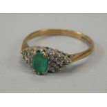 A 9ct gold dress ring, claw set with green stone, flanked by small diamonds, on a part pierced