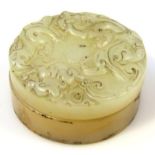 A 20thC Chinese jade box, of circular outline, carved with scrolls and flower heads, with a