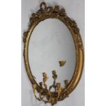 A 19thC gilt wood girandole mirror, of oval outline, surmounted by scrolls, ribbons and