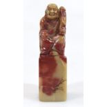 A Chinese Qing style soapstone desk seal figure, formed as a seated gentleman in flowing robes,