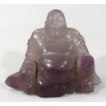 A 20thC Chinese amethyst coloured glass sculpture of Buddha, in seated pose, in flowing open