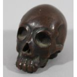 A Meiji period Japanese bronze figure of a skull, raised gilt seal mark beneath, 7cm wide.