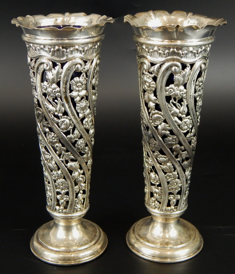 A pair of Edwardian silver specimen vases, with pierced floral design, with blue glass liners, and