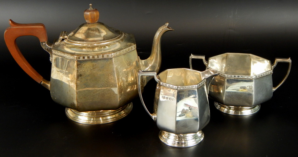 A George V Art Deco silver three piece tea service, comprising teapot, 16cm high, with ebonised