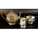 A George V Art Deco silver three piece tea service, comprising teapot, 16cm high, with ebonised