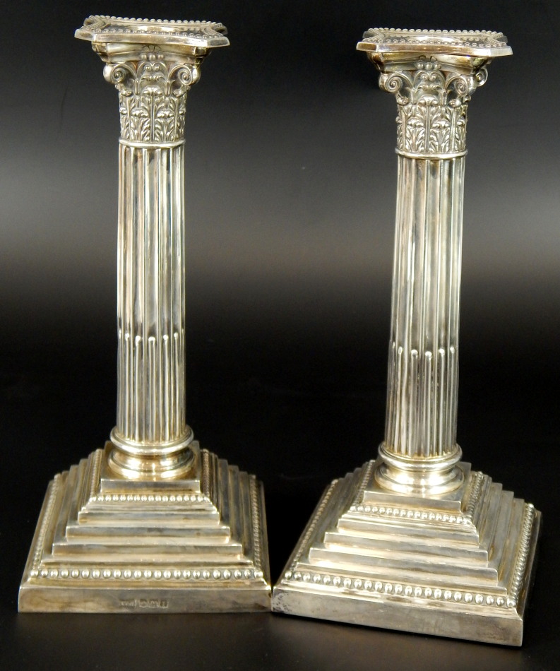 A pair of George V silver Corinthian column table candlesticks, on reeded and fluted stem, with