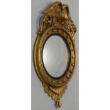 A Regency giltwood and gesso convex wall mirror, with an eagle crest, flanked by two scroll