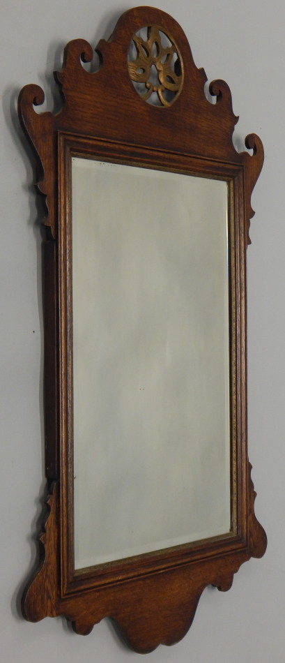An oak fret frame wall mirror, in George III style, the shaped crest with a pierced parcel gilt
