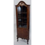 A walnut and burr walnut corner cabinet, the domed top with a moulded edge above a shell carving