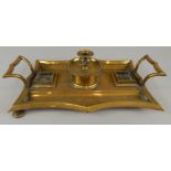 A 19thC brass inkwell, with two handles and a removable central chamberstick, on bun feet,