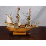 A scale model of a two masted British Galleon, flying the red ensign, on a wooden stand, 50cm long