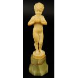 An early 20thC ivory figure of a young boy holding an apple, on carved stepped onyx base