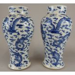 A pair of 19thC Chinese baluster vases, decorated overall with dragons in blue, stamped to