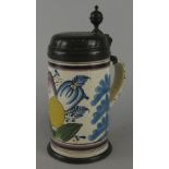 A German faience tankard, decorated with flowers, leaves etc., with a pewter mount, bearing the