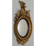A Regency giltwood and gesso convex wall mirror, mounted with an eagle and foliate scroll crest, the