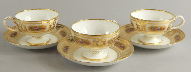 Three Victorian porcelain cups and saucers, each decorated with flowers within elaborate gilt