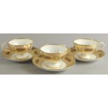 Three Victorian porcelain cups and saucers, each decorated with flowers within elaborate gilt