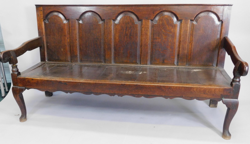 An early 18th/late 17thC oak settle, with a panelled back, shaped arms and planked seat on