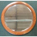 An early 20thC circular oak wall mirror, with a bevel plate, 66cm dia.