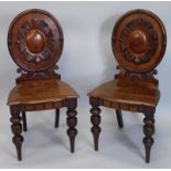 A pair of Victorian hall chairs, each with a oval cartouche shaped back, a solid seat with moulded