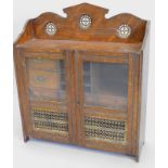 An early 20thC oak smoker's cabinet, the raised back inset with pierced gilt metal roundels above