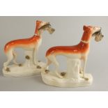 A pair of mid 19thC Staffordshire models of greyhounds, each with a hare in its mouth, on an oval