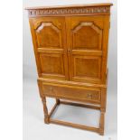 An oak cupboard, the top with a moulded edge above a pair of panelled doors each with burr oak