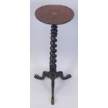 An ebonised mahogany torchere, the circular top with a moulded edge above a spirally turned