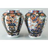 A pair of Japanese style Imari vases, of octagonal form, each decorated with buildings, flowering