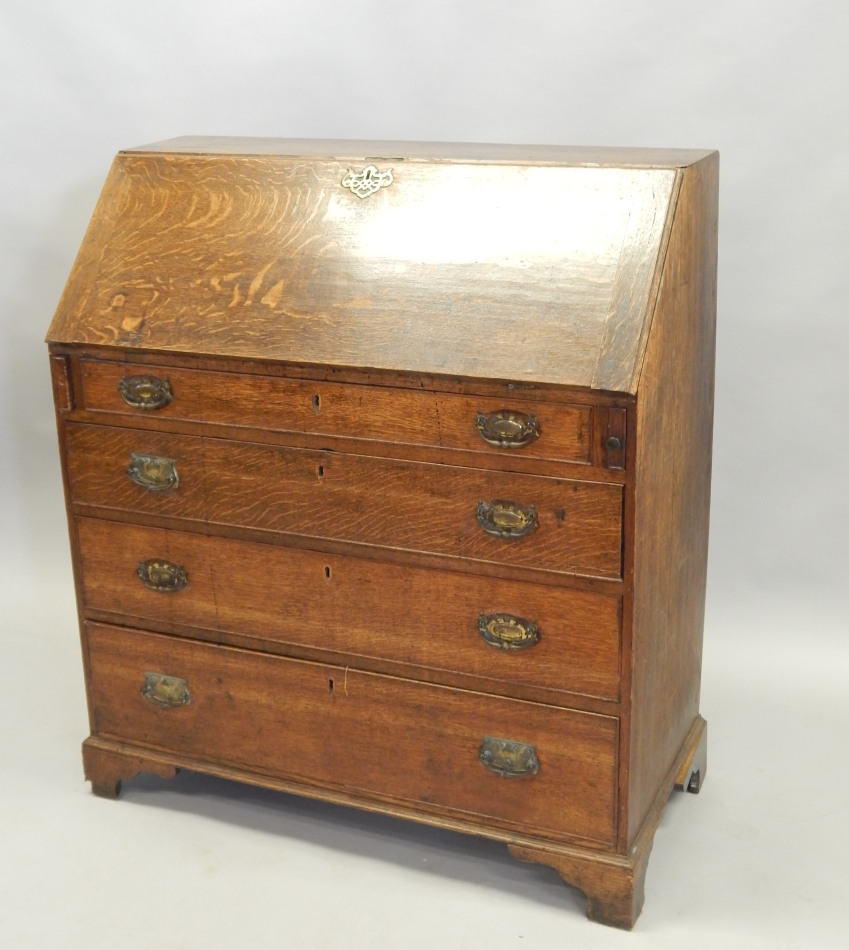 A George III oak bureau, the fall enclosing a fitted interior, above four graduated drawers, on