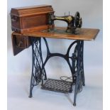 A late 19th/early 20thC Singer sewing machine, on a walnut and cast iron treadle base, 87cm wide.