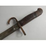 An early 20thC bayonet, with metal scabbard, curved metal guard and wooden hilt with metal pommel,