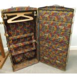 An early 20thC canvas and brass bound wardrobe trunk, with various luggage labels.