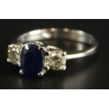 An 18ct white gold sapphire and diamond ring, with central oval cut sapphire, 6.4mm x 4.8mm x 2.8mm,