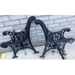 A pair of Victorian black painted cast iron garden bench ends, each decorated with leaves etc.