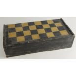 An early 20thC ebonised chess board, hinging to reveal a fitted interior with a quantity of