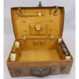 An early 20thC leather dressing case, bearing the initials HNDM, containing a number of ivory