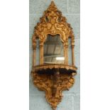 A Continental gilt wood and gesso wall bracket, the later mirror plate surrounded by leaf craft