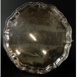 An Elizabeth II silver salver, with a raised pie crust type border on shaped skull carved feet,