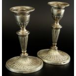 A pair of late Victorian silver candlesticks, each with a reeded oval column and tapering base,