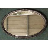 A 20thC oval oak wall mirror, with a bevel plate, 80cm wide