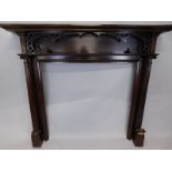 An early 20thC mahogany fire surround, the mantel with a moulded edge above a blind fret, carved