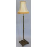 A early 20thC brass standard lamp, with a cylindrical column, square base on bun feet.