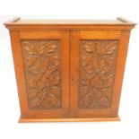 An early 20thC oak small cabinet, with moulded corners, above two floral carved doors, including a