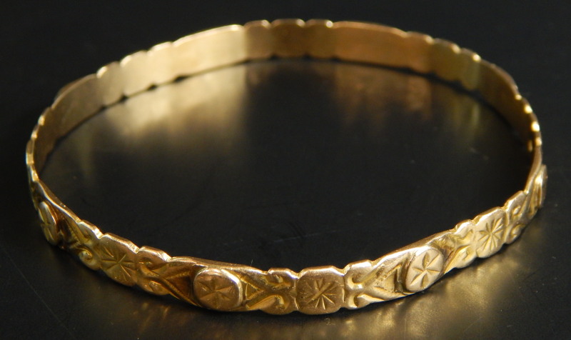 A bangle, of floral engraved design, with star design, yellow metal, unmarked, 14.2g all in.